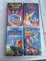 Four Disney VHS tapes on a flat surface: The Return of Jafar, Beauty and the Beast, The Lion King, Toy Story.