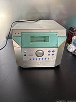 Front view of JBL VMA MP3 audio receiver showing power cable, green display and button layout.