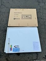 Magnetic whiteboard unboxed with its cardboard packaging placed behind it along with all accessories spread in front