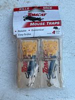 Front view of Tomcat mouse traps in retail plastic packaging showing 2 traps visible, yellow bait holders, and branded cardboard backing.