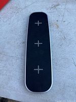 Top view of black wireless charging station showing three charging spots marked by plus signs.