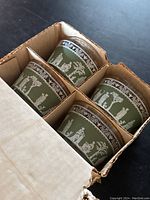 Top view showing 4 green custard cups with white Hellenic Greek-style figures and patterns in original box