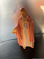 Front and side views of ceramic nativity figure showing detailed robe, cloak, and facial features