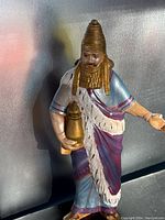 Full view of ceramic nativity figure showing painted details and posed holding a vessel