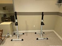 Pair of fully adjustable weight stands for bench press or squats with black adjustable supports and sturdy silver bases.