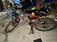 Side view of red and black Gary Fisher men's mountain bike with tires, pedals, and kickstand visible