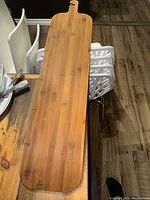 Photo of entire long bamboo charcuterie board laid flat showing wood grain and handle with hole.