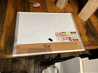 Top view of magnetic whiteboard calendar with cork board on wooden table including magnetic labels
