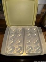 Top view of clear plastic tray with 12 egg holders inside yellow base