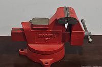 Side view of the red 6-inch bench vise, showing the jaws and swivel base.