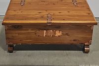 Front view of cedar blanket chest closed, showing copper decorative hardware and curled feet.