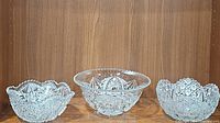 Three clear cut crystal bowls arranged in a row, showing varying sizes and intricate cut star patterns