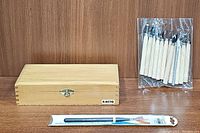 Closed X-ACTO wooden box alongside pack of wooden carving tools and sealed artist paintbrush.