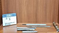 Photo showing 5 Woodcut Knife box, iron chisels, mill file and flooring tool on wooden surface with wooden background