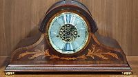 Front view of Howard Miller Vanderbilt clock showing wooden arch case and floral inlay