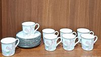 8 Noritake New Decade cafe cups displayed next to 8 matching saucers stacked