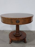 Front view of the solid rosewood drum table showing the round top, pedestal base, and claw feet with drawer pull visible.