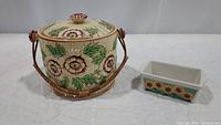 Ceramic cookie jar with lid and wooden handle alongside rectangular stoneware loaf pan with sunflower decoration