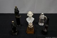 Front view of all six vintage Avon men's cologne decanters arranged on a black surface showing variety in design and condition