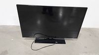 Front view of black 40-inch Samsung TV on base with power cord.