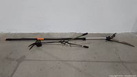 Full view of tree cutter and yard clippers lying on concrete floor showing overall condition and length of handles.
