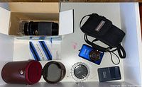 Overview of all items: camera, charger, camera case, lens in box with manual, lens case, polarizer filter