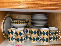 12 piece set of Sasaki Tuscany fine Japanese china with a diamond pattern in dark green and beige, displayed in a wooden cabinet