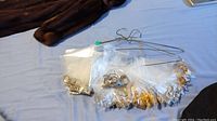 Photo of multiple earrings and necklaces packaged separately in plastic bags held on a metal hanger.