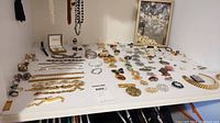 Top-down view showing full assortment of bracelets, rings, brooches, pins, watch, and pendant necklace