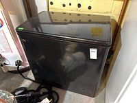 Closed black chest freezer with visible Danby logo on front, power cord seen to side.