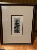 Full view of framed etching in a brown wood frame with cream matting and gold inner border