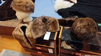 View showing two mink collars and two mink hats displayed on a table with one hat on a mannequin head.