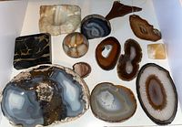 Overview photo of 13 polished geodes and mobile wood hanger arranged on flat surface.