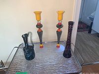 Photo showing two colorful Romanian glass candlestick holders and two decorative glass vases placed on a silver-colored tray.