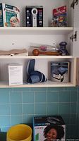 Shelf containing various boxed medical devices including blood pressure monitors, glucose tester, a vibrating neck massager and handheld massagers.