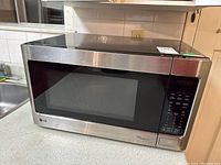 Front view of LG stainless steel microwave on countertop showing door and control panel.