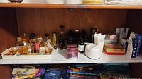 Wide view of shelf with multiple perfume bottles, tubes, boxes, and skincare products including a variety of scents and lotions