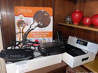 Photo shows two black Sony Dream Machines FM/AM clock radios model ICF-C212, Ultonic clock radio, and boxed OttLite Dual LED Precision Magnifier Set with dual magnification lenses.
