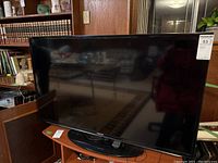 Front view of Samsung flat screen TV showing large 46 inch screen and base stand, set on a table.