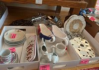 Photo of silver plated and ceramic serving ware including gravy boats, saucers, cup, plates and metal trivets