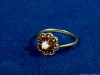 Front view of ring showing cluster head with opal center and garnet halo