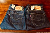 Two folded pairs of Levi's blue jeans folded to show back pockets and tags, one 501 and one 505 series.