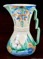 Side profile showing the hand-painted stork, foliage, flowers, and geometric handle of the Wade Heath jug.