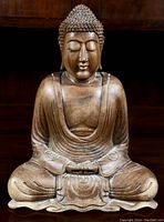 Front view of the hand carved wooden Buddha showing detailed facial features, robe folds, and seated posture.