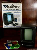 Front view showing original box, console, controller, game cartridge, and overlays