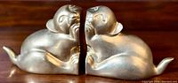 Side view of the brass cat bookends facing each other, showing their shape and detail.