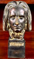 Close front view of bronzed Franz Liszt bust with detailed facial features and inscription on base