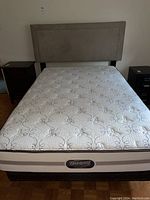 Full view of the bed with upholstered headboard, mattress, and boxspring on a wooden frame.