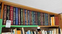 Shelf of hardcover and paperback classic novels, showing titles and authors with a MaxSold lot tag number 856