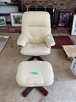 Front view of ivory leather swivel chair with matching ottoman on wooden swivel bases